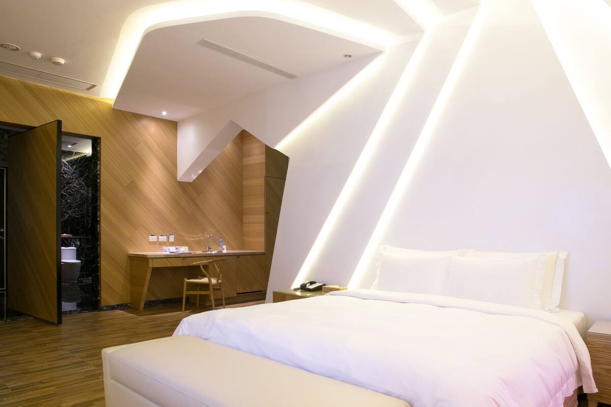 A modern hotel room with a bed, a desk, and a chair.