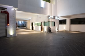 Un vaste espace intérieur doté d’une architecture moderne, comprenant une colonne centrale, un comptoir d’accueil et une porte fermée portant le numéro 101.