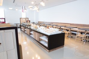 A modern cafe with a central counter displaying food items, wooden tables and chairs, and a clean, minimalist interior. - All-Ur Boutique Motel - Hua-Lian Branch (Ji'an)