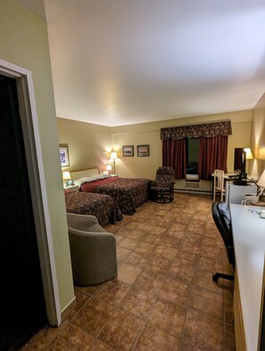 A hotel room with a bed, two chairs, a desk, and a window with curtains. - Hotel Motel de la Montagne (Saint-Pascal)