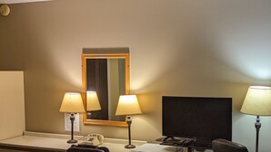 Ein Hotelzimmer mit Schreibtisch, zwei Stühlen, einem Fernseher und zwei Lampen.