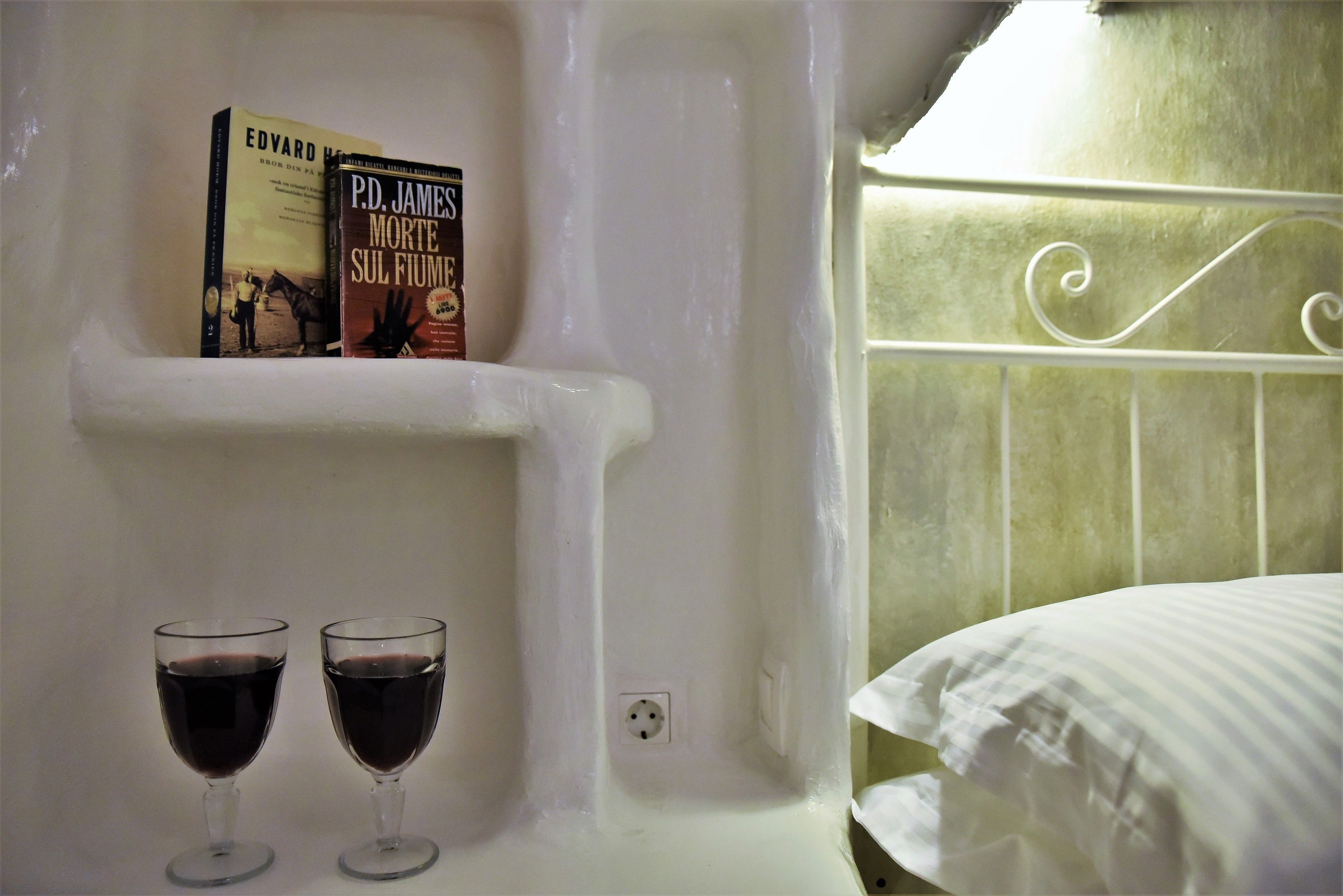 Una repisa blanca con dos copas de vino y dos libros.