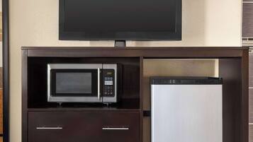 Una kitchenette con microondas, refrigerador y televisor de pantalla plana montado en la pared.
