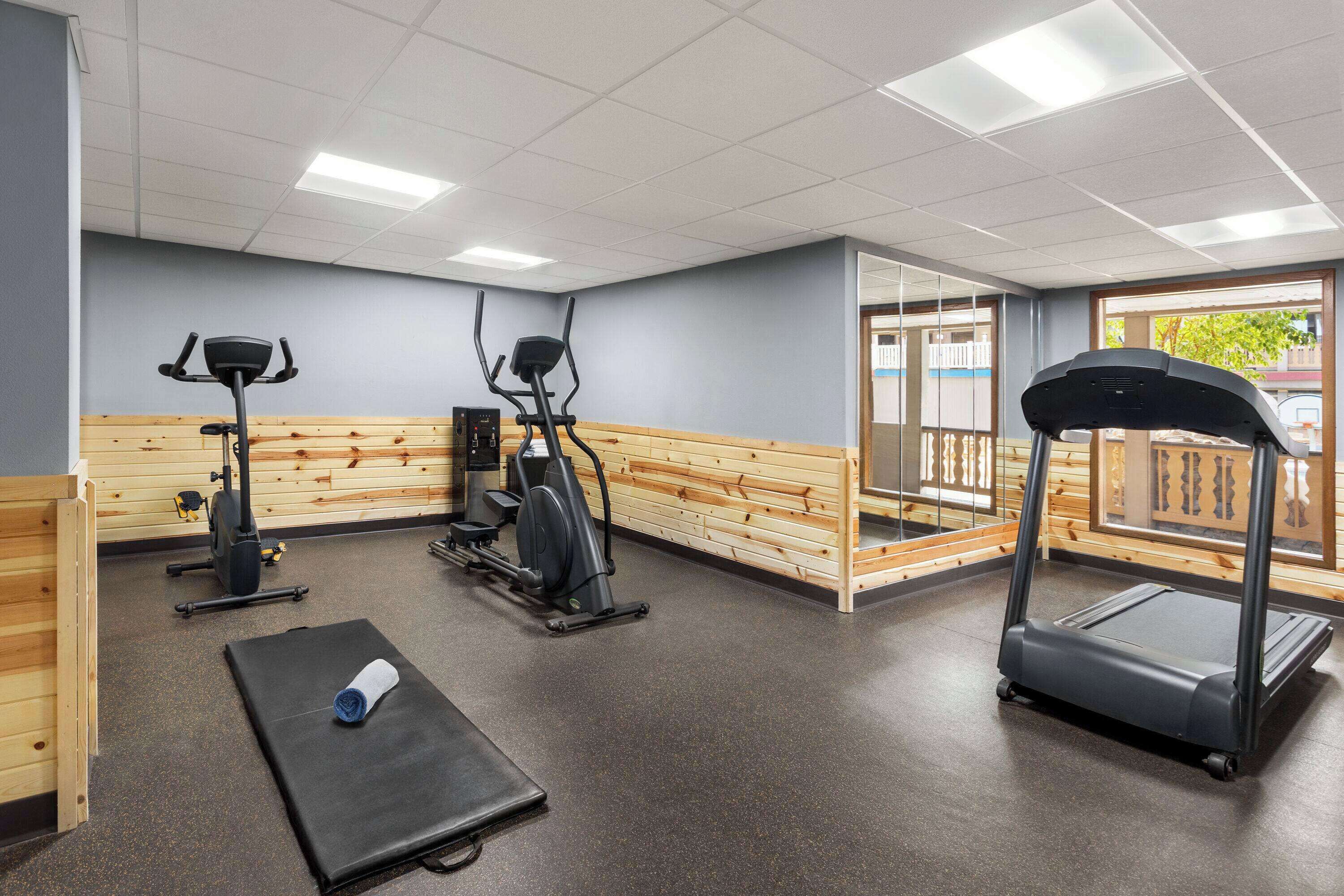 Una sala de gimnàstica amb equipament d'exercici, una cinta de córrer i una paret de fusta.