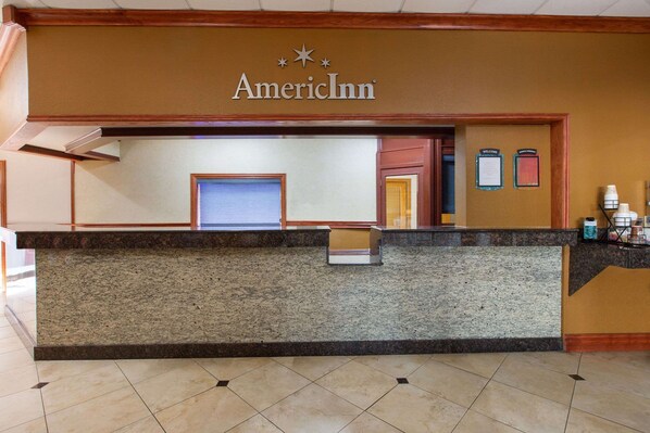A reception desk at AmericInn with a stone counter, a reception area, and a wall-mounted information board. - AmericInn by Wyndham La Crosse Riverfront-Conference Center (La Crosse)