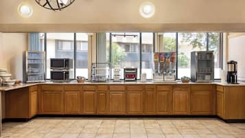 A kitchen with wooden cabinets, a microwave, a coffee maker, and a refrigerator.