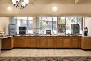 A kitchen with wooden cabinets, a microwave, a coffee maker, and a refrigerator. - AmericInn by Wyndham La Crosse Riverfront-Conference Center (La Crosse)