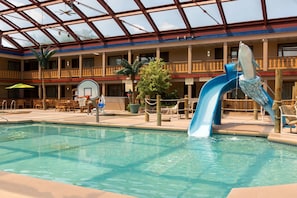 An indoor pool with a blue slide, lounge chairs, and a basketball court. - AmericInn by Wyndham La Crosse Riverfront-Conference Center (La Crosse)