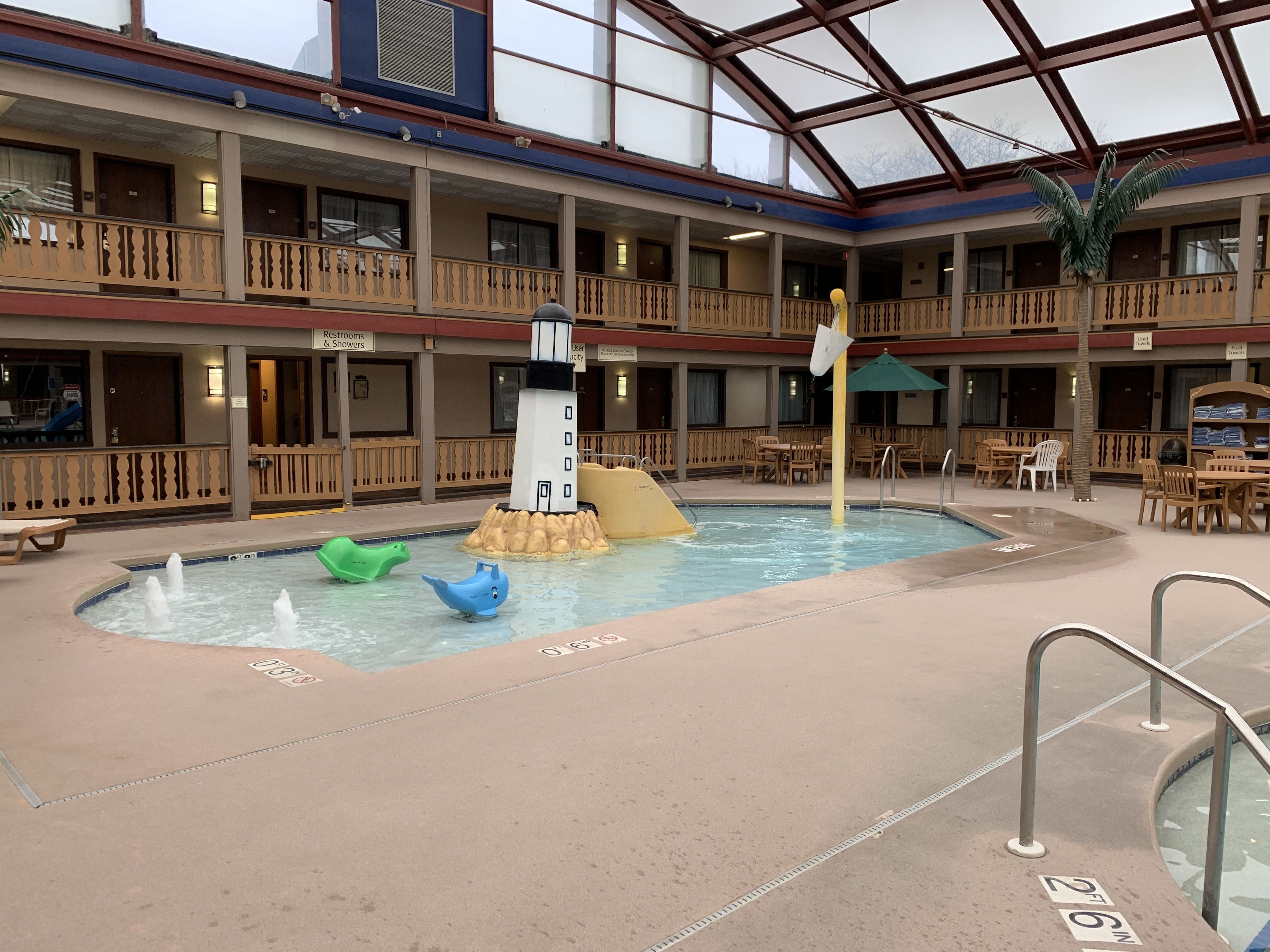 Un área de piscina interior con decoración de faro, varios niveles con balcones y diferentes opciones de asientos.