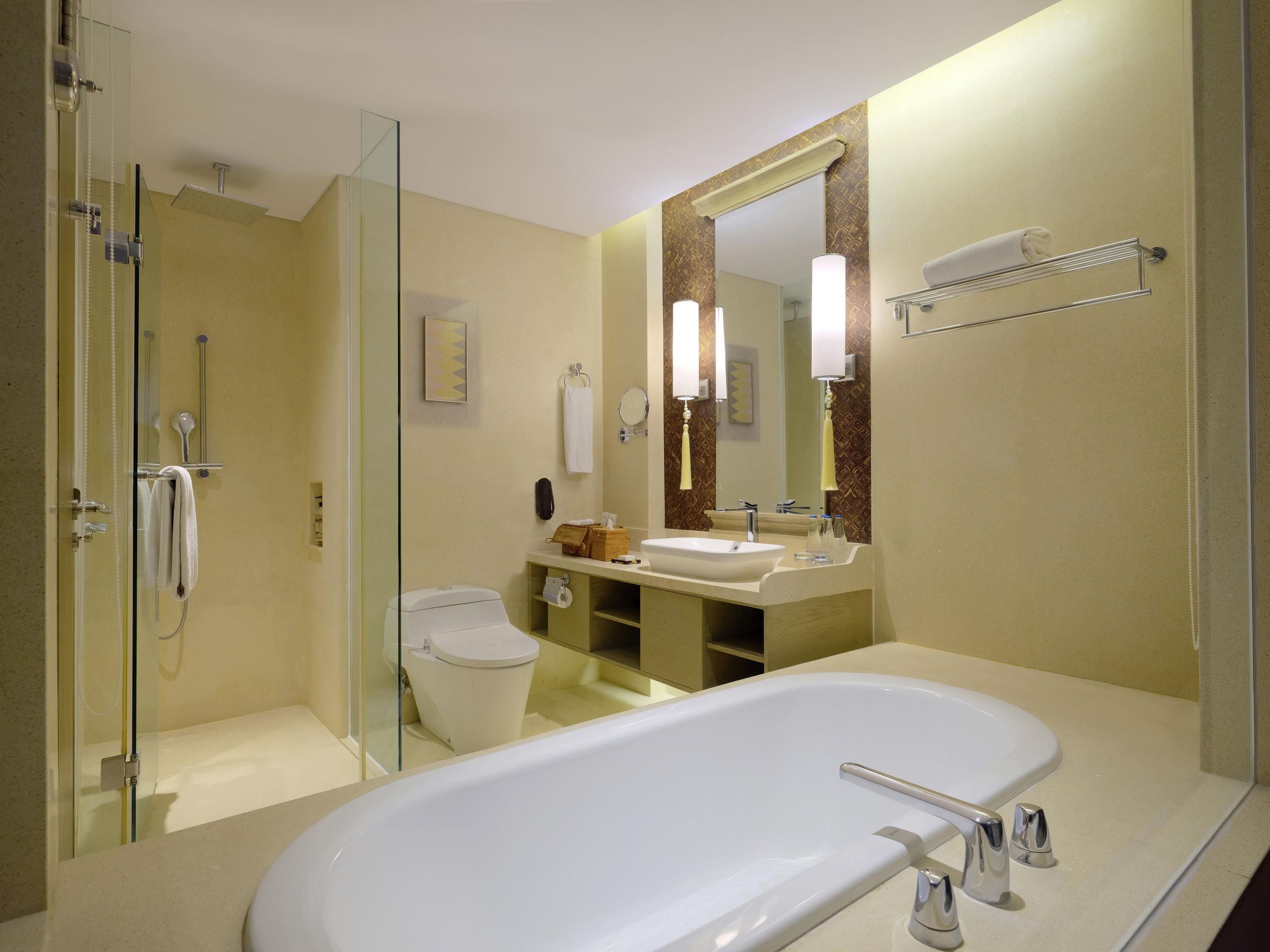 A modern bathroom with a glass-enclosed shower, a white bathtub, and a vanity with a large mirror.