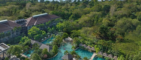 Relax by the resort's central swimming area surrounded by lush greenery and multiple pools.