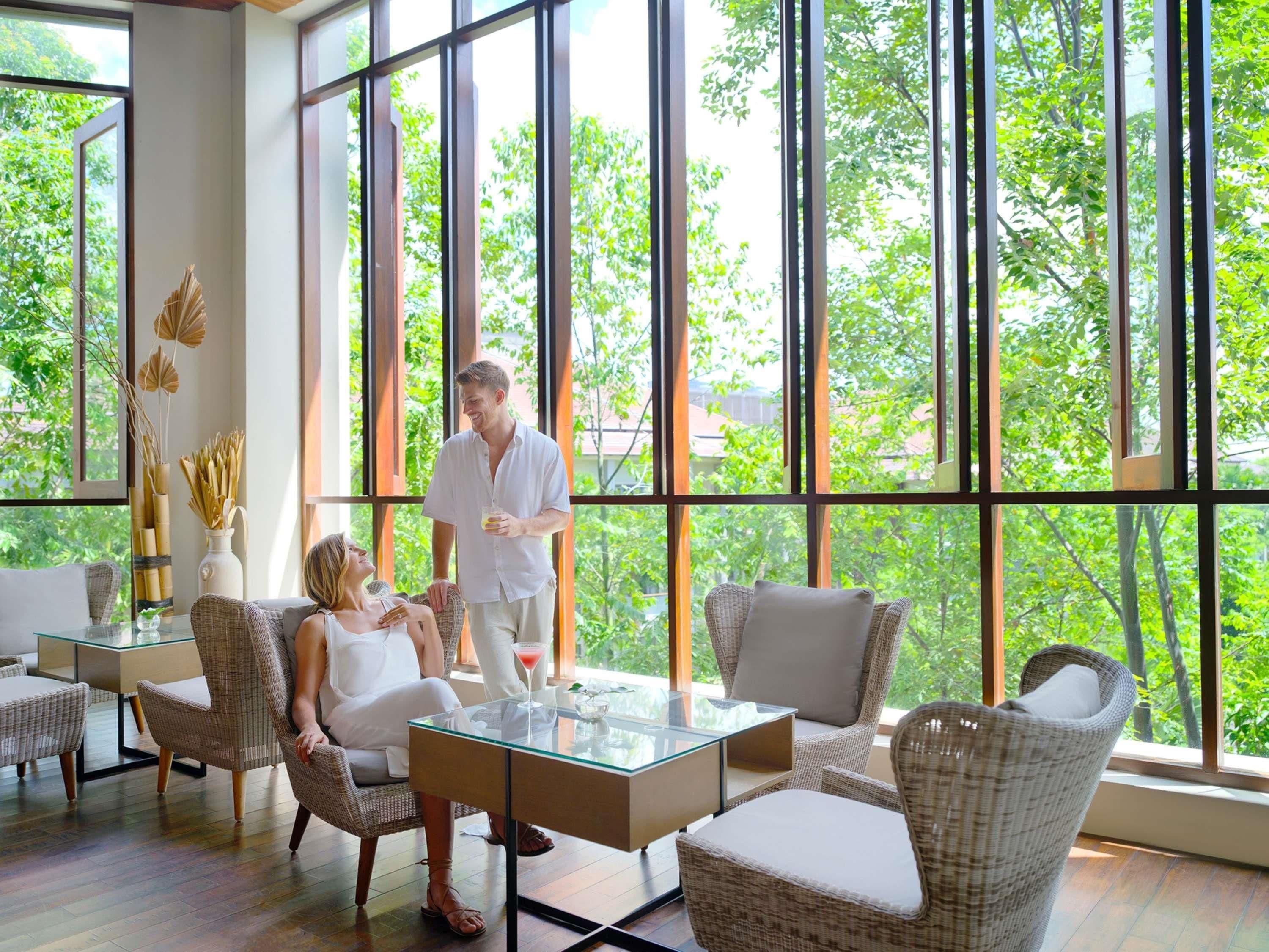 A modern room with large windows, wicker furniture, and a glass table.