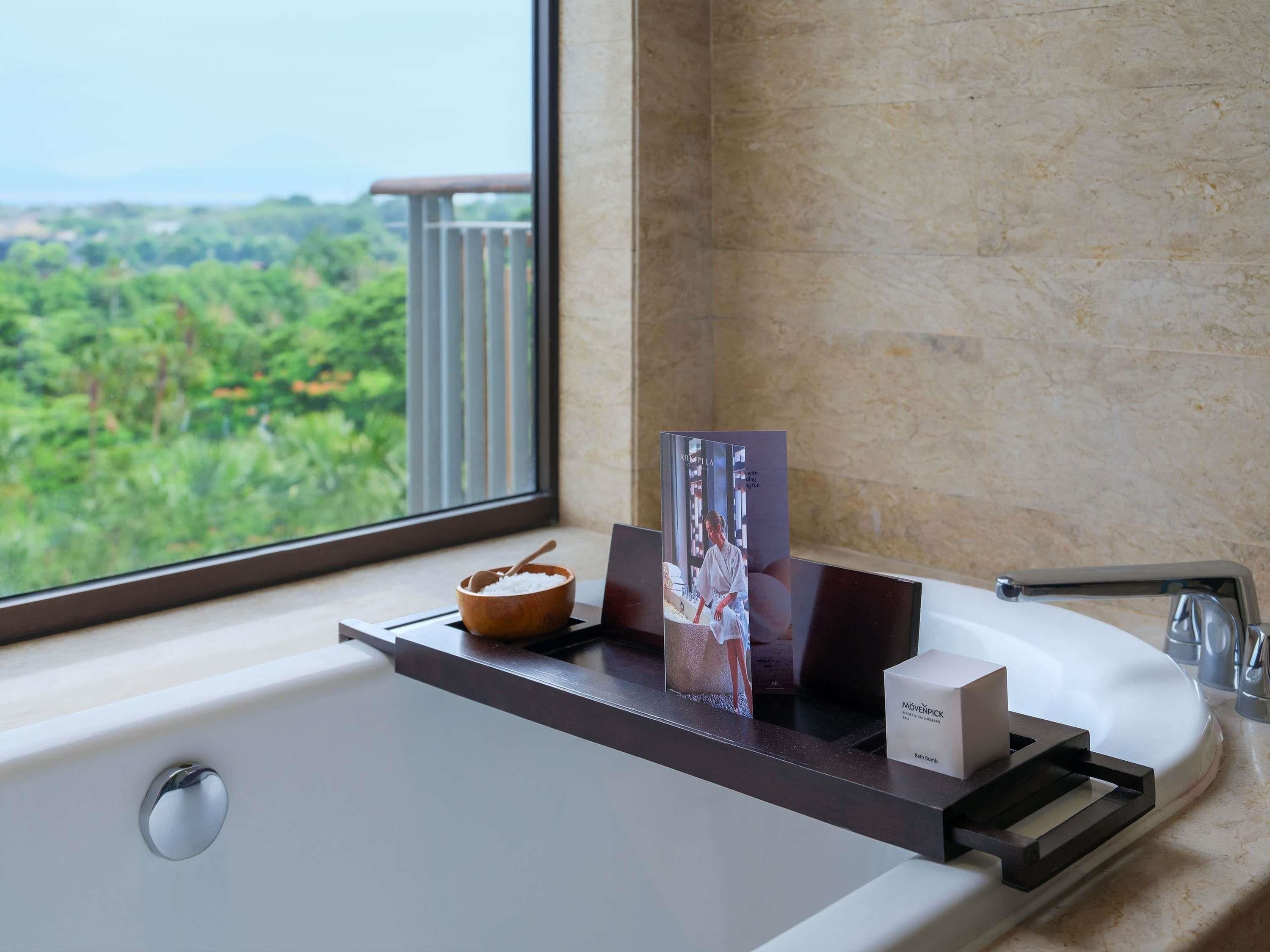 Un baño con una bañera, un cuenco de madera, una revista y un dispensador de jabón.