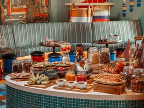 A buffet with various food items, including fruits, pastries, and beverages.