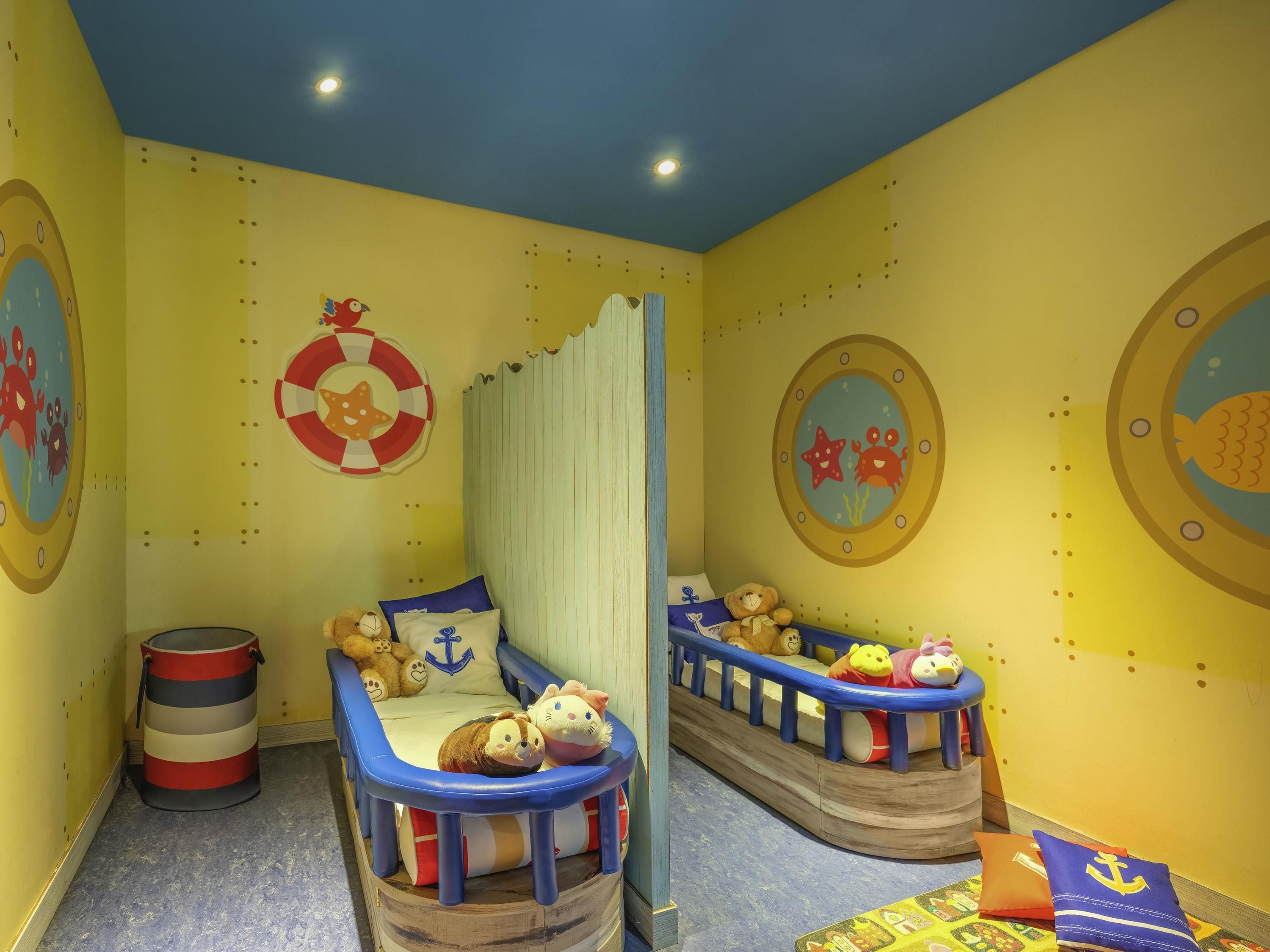 A children's room with a nautical theme, including a bed with a ship design, a small boat-shaped bed, and wall decorations featuring sea creatures.