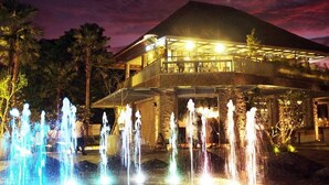 Een hotel met een fontein en een overdekt terras, met een berg op de achtergrond.