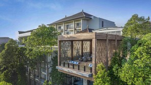 Een modern meerlaags gebouw met een terras op het dak, omgeven door weelderige begroeiing.