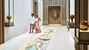 Een moderne hotellobby met een centraal waterkunstwerk, een decoratieve wand en een vloer met een patroon.