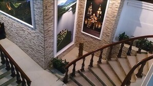 A staircase with stone walls and wooden railings, leading to a landing with a large poster of a castle. - Hotel Arboledas (Talpa de Allende)
