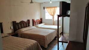 A hotel room with three beds, a ceiling fan, a TV on a stand, and a window with curtains. - Hotel Arboledas (Talpa de Allende)