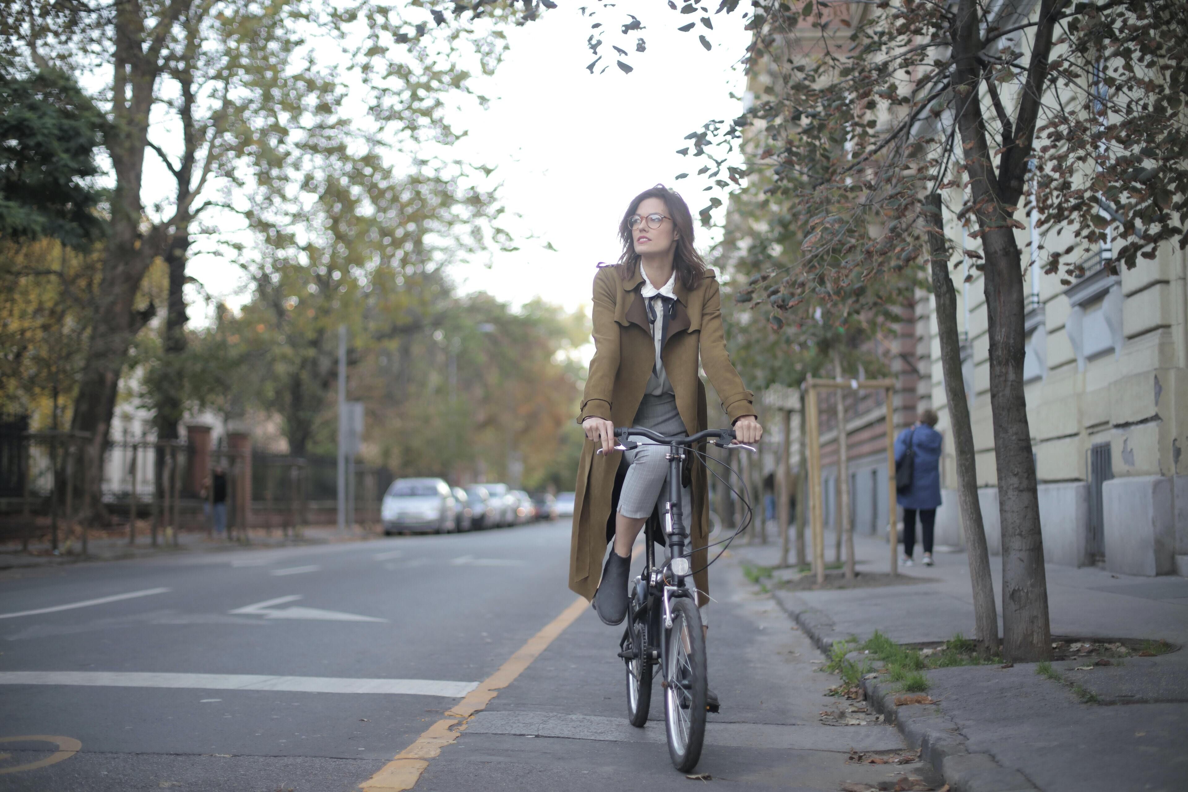 Una persona montando en bicicleta por una calle arbolada.