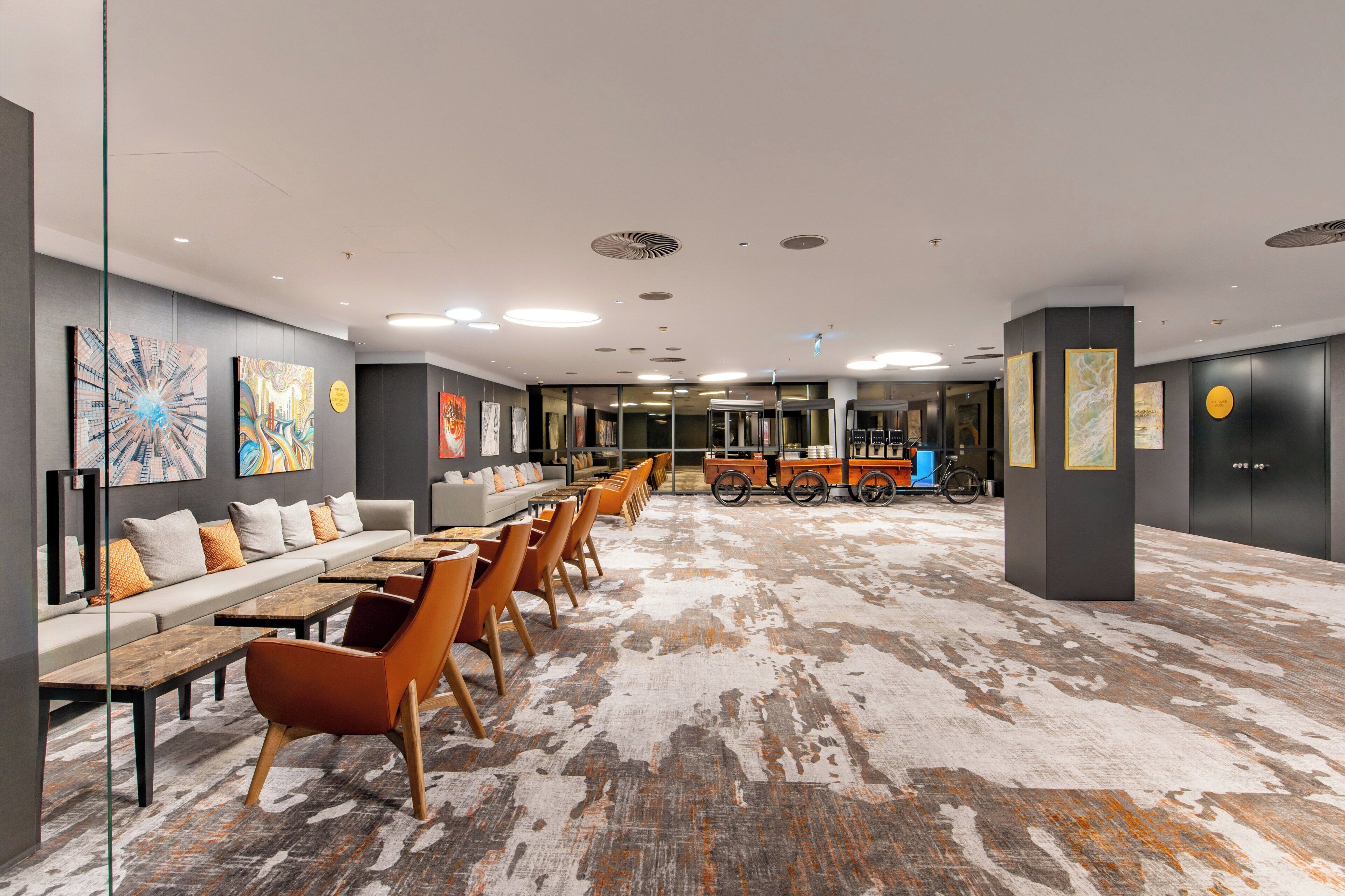 A spacious hotel lobby with a long reception desk, comfortable seating areas, and modern artwork on the walls.