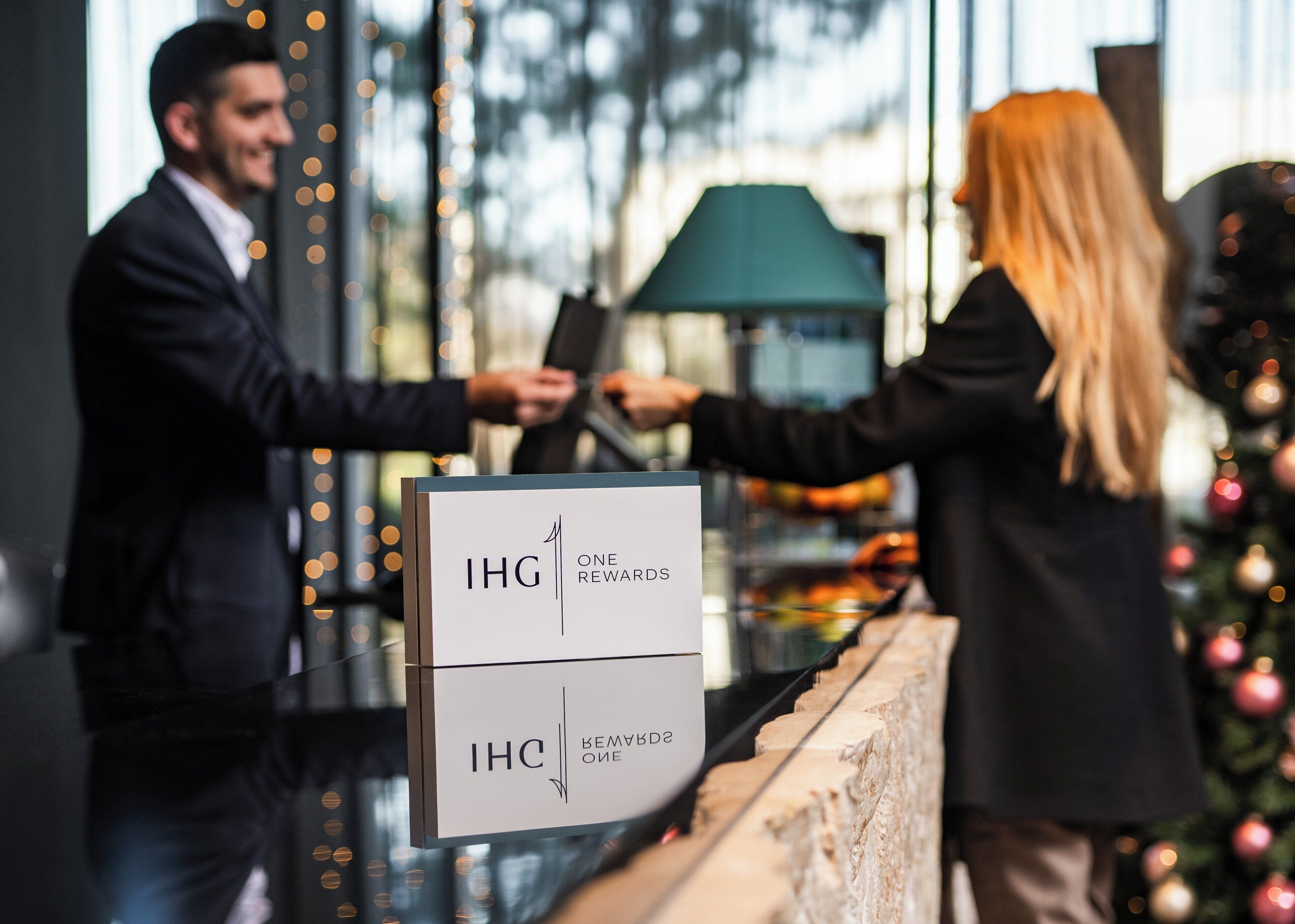 Un hombre y una mujer en la recepción de un hotel, intercambiando una tarjeta por una llave de la habitación.