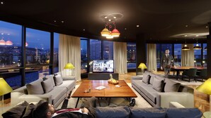 Een moderne hotelkamer met een groot stadsgezicht, een gezellige zithoek en een eettafel.