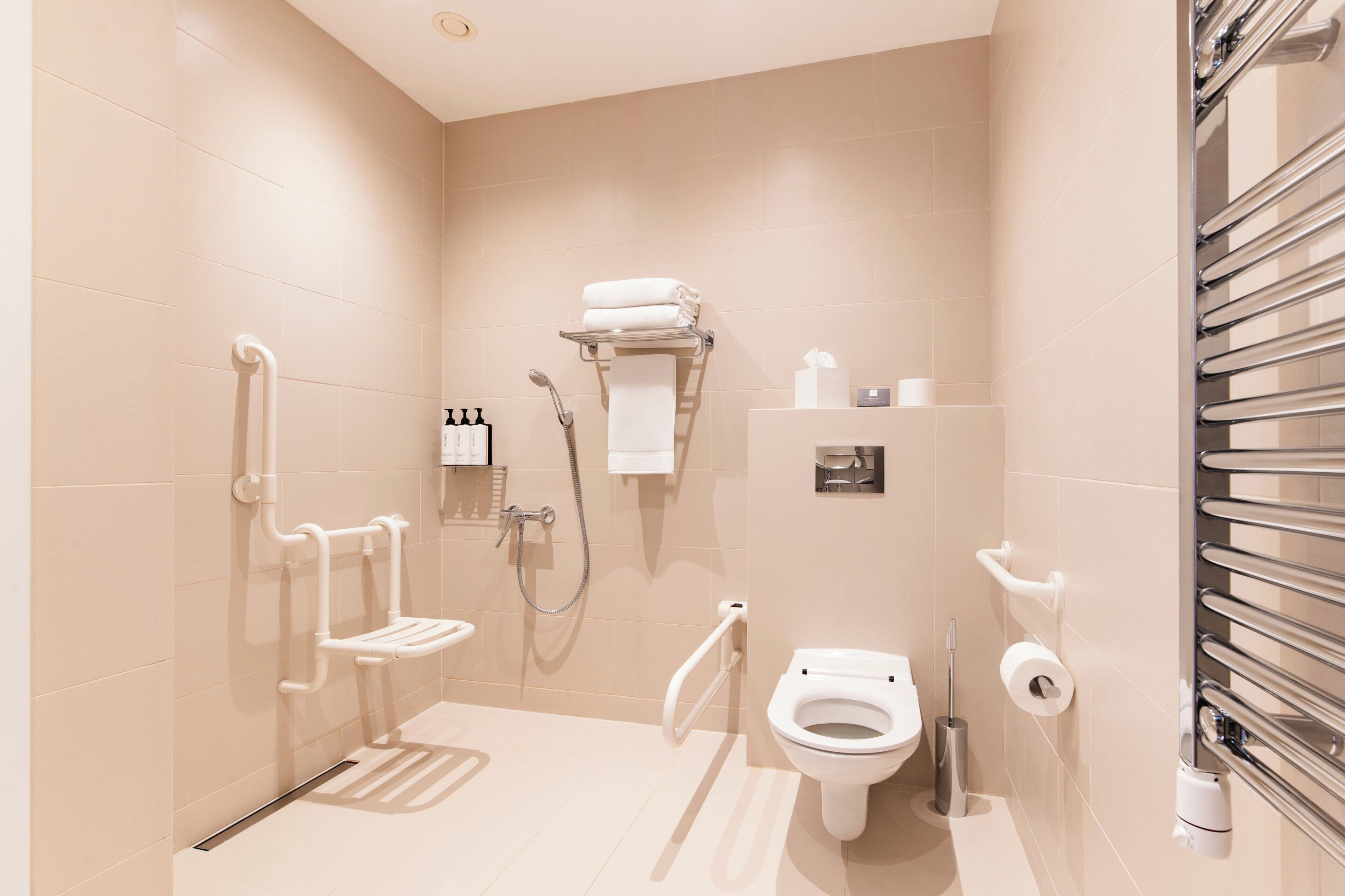 A modern bathroom with a walk-in shower, grab bars, a toilet, and a towel rack.