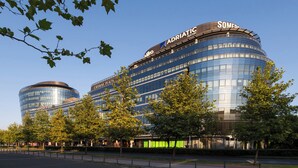 Een modern gebouw met een gebogen gevel, met daarop de naam "Adriatic Bank" en "Crown Plaza" aan de zijkant.