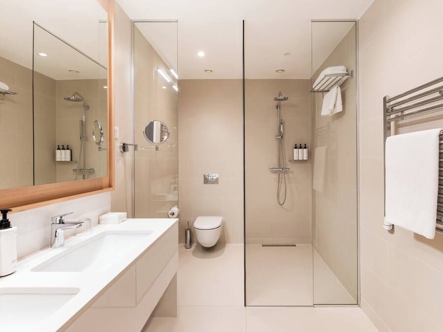 Un bagno moderno con doccia vetrata, uno specchio grande e un lavandino bianco.