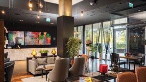 Een moderne lobby met een bank, stoelen, een bijzettafeltje en kunstwerken aan de muur.