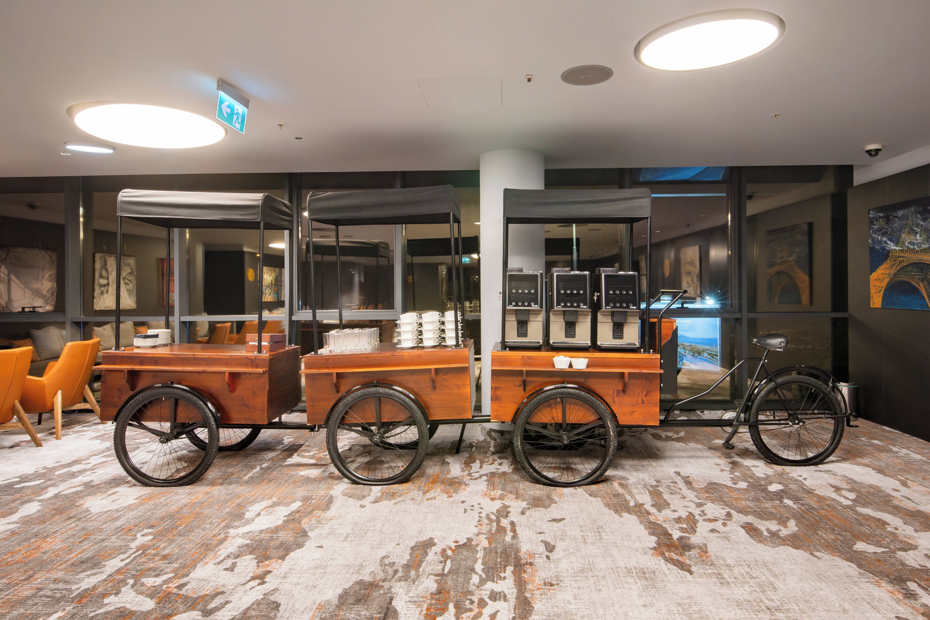 Un interior moderno con piso de madera rústica, una bicicleta y un carrito con utensilios de cocina.