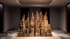 Een moderne kunstinstallatie in een hotel lobby met een patroon tapijt en donkere muren.