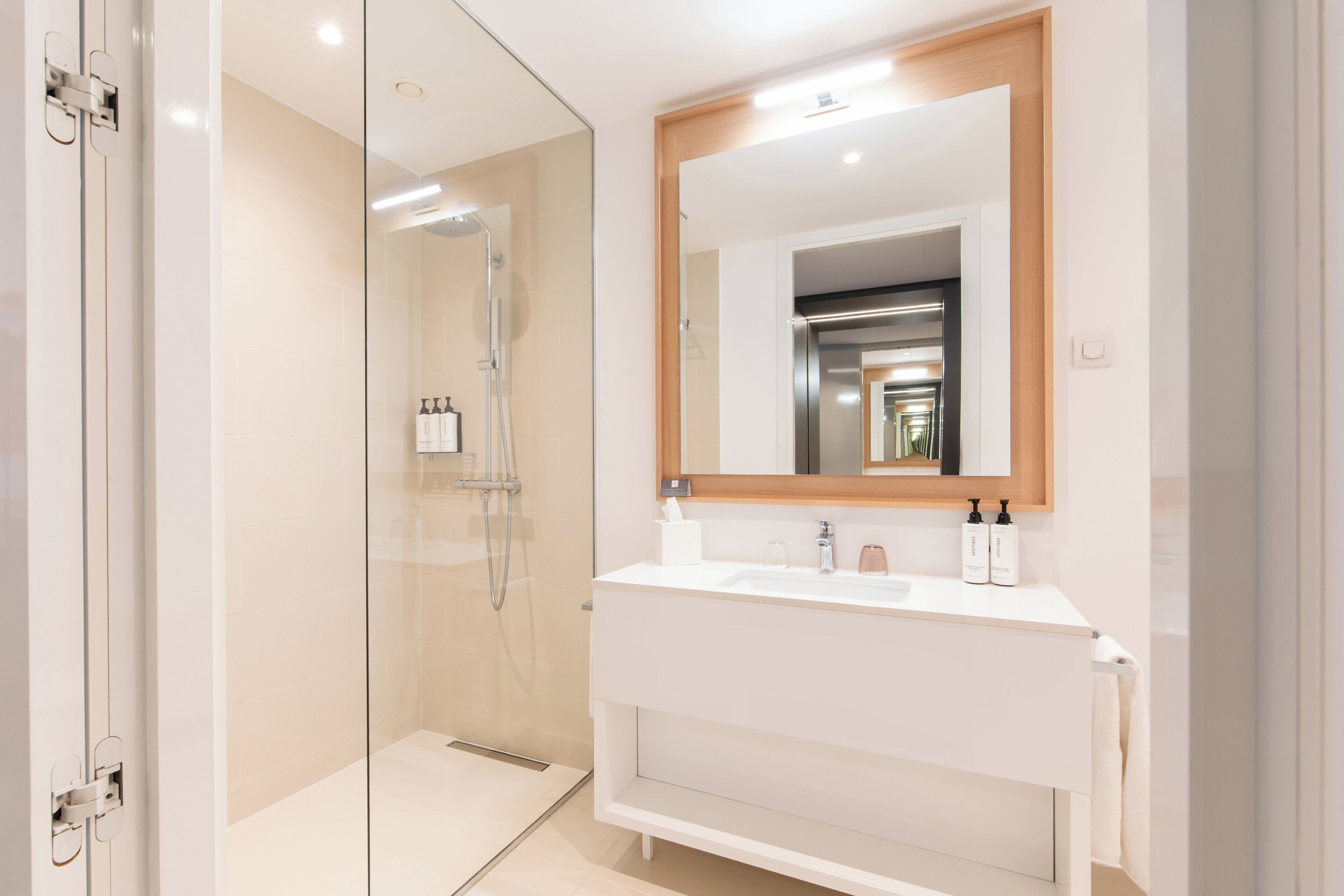 Une salle de bain moderne avec une douche à parois de verre, un meuble-lavabo blanc avec un miroir et une serviette accrochée au mur.