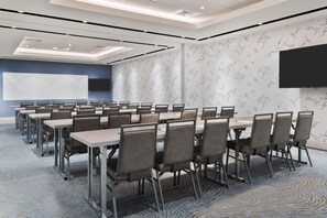 Une salle de conférence équipée d’un grand écran, de plusieurs tables et de chaises.