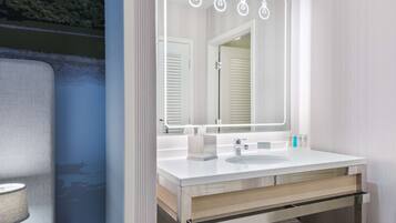 A modern bathroom with a large mirror, a white sink, and a towel rack.