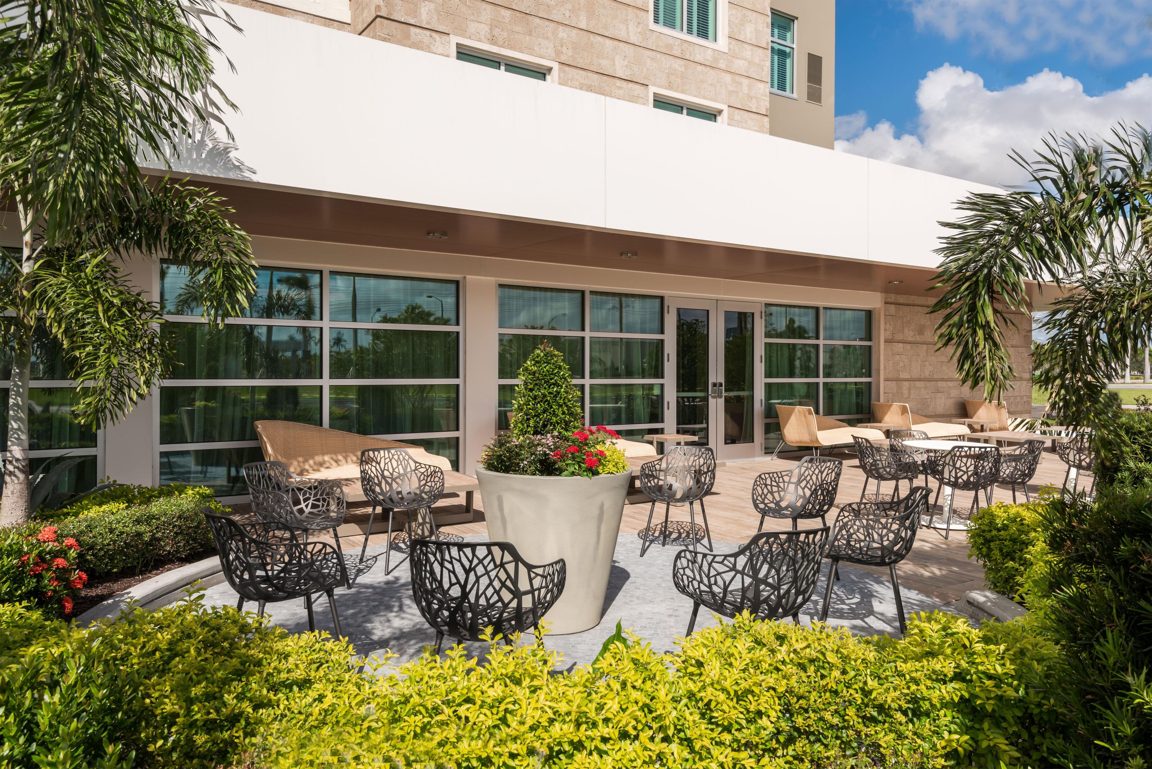 Eine Außenpatio-Terrasse mit Sitzgelegenheiten und einem großen Pflanzgefäß mit Blumen.
