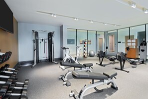 Une salle de sport moderne équipée de divers appareils d’exercice, notamment des tapis de course, des appareils de musculation et des poids libres.
