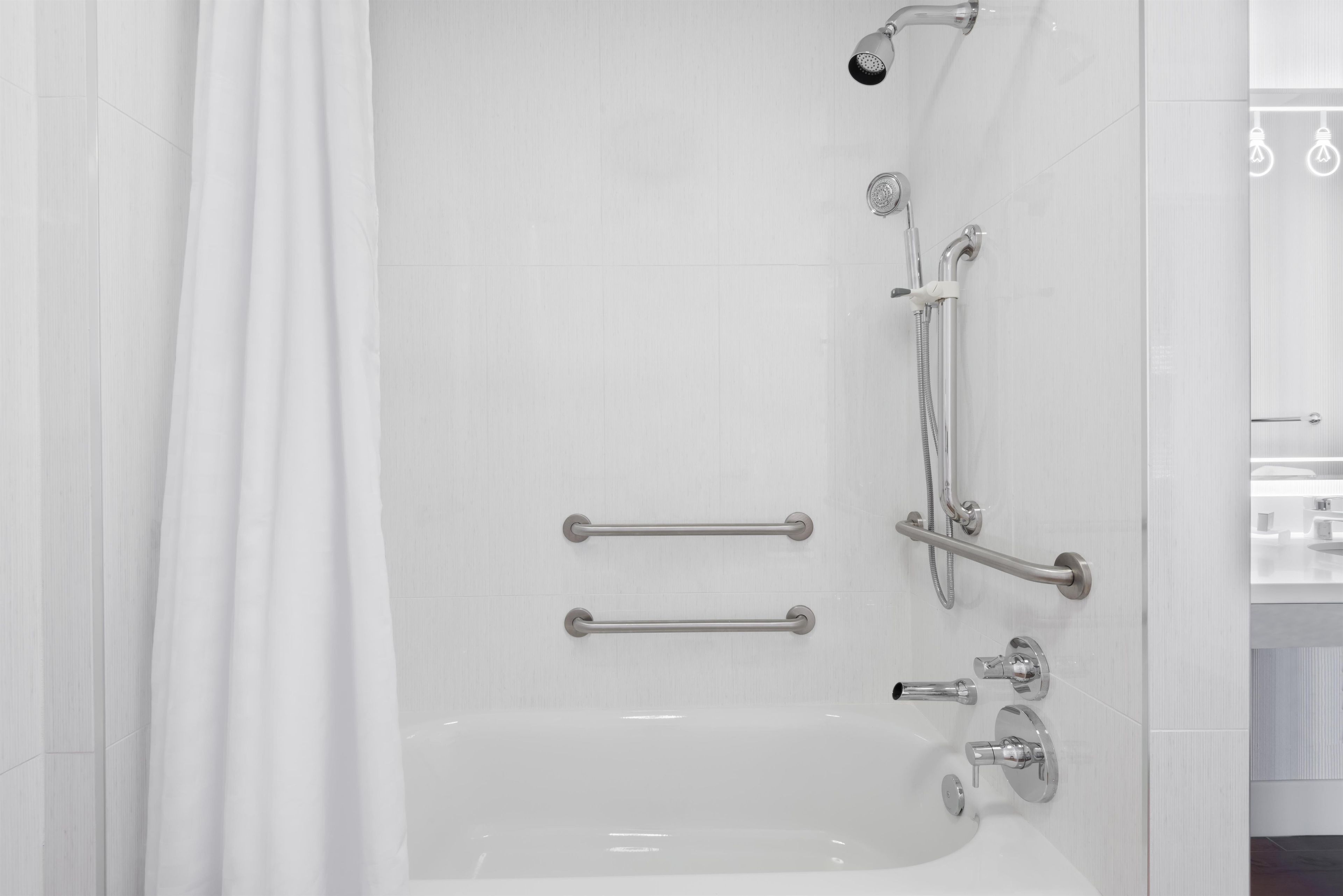 A modern bathroom with a walk-in shower, grab bars, and a handheld showerhead.