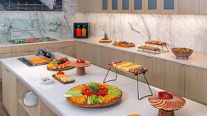 A buffet setup with various food items and a glass display case with bottles. - Homewood Suites by Hilton Sarasota Lakewood Ranch (Sarasota)