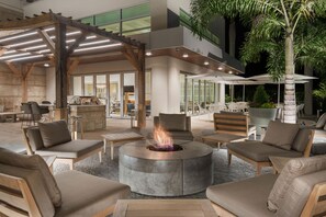 Un espace extérieur aménagé avec un foyer circulaire, des chaises en bois et une structure en forme de pergola.