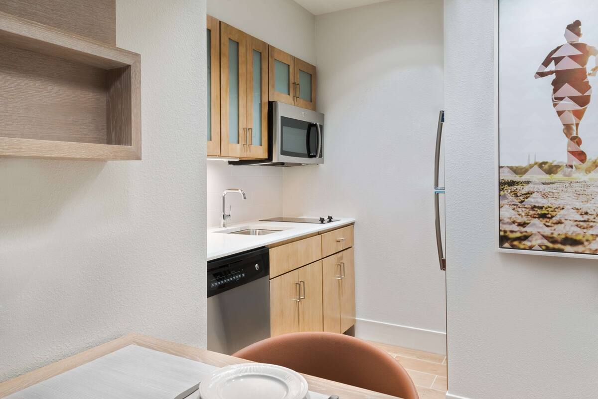 A compact kitchen with wooden cabinets, a microwave, a dishwasher, and a refrigerator.