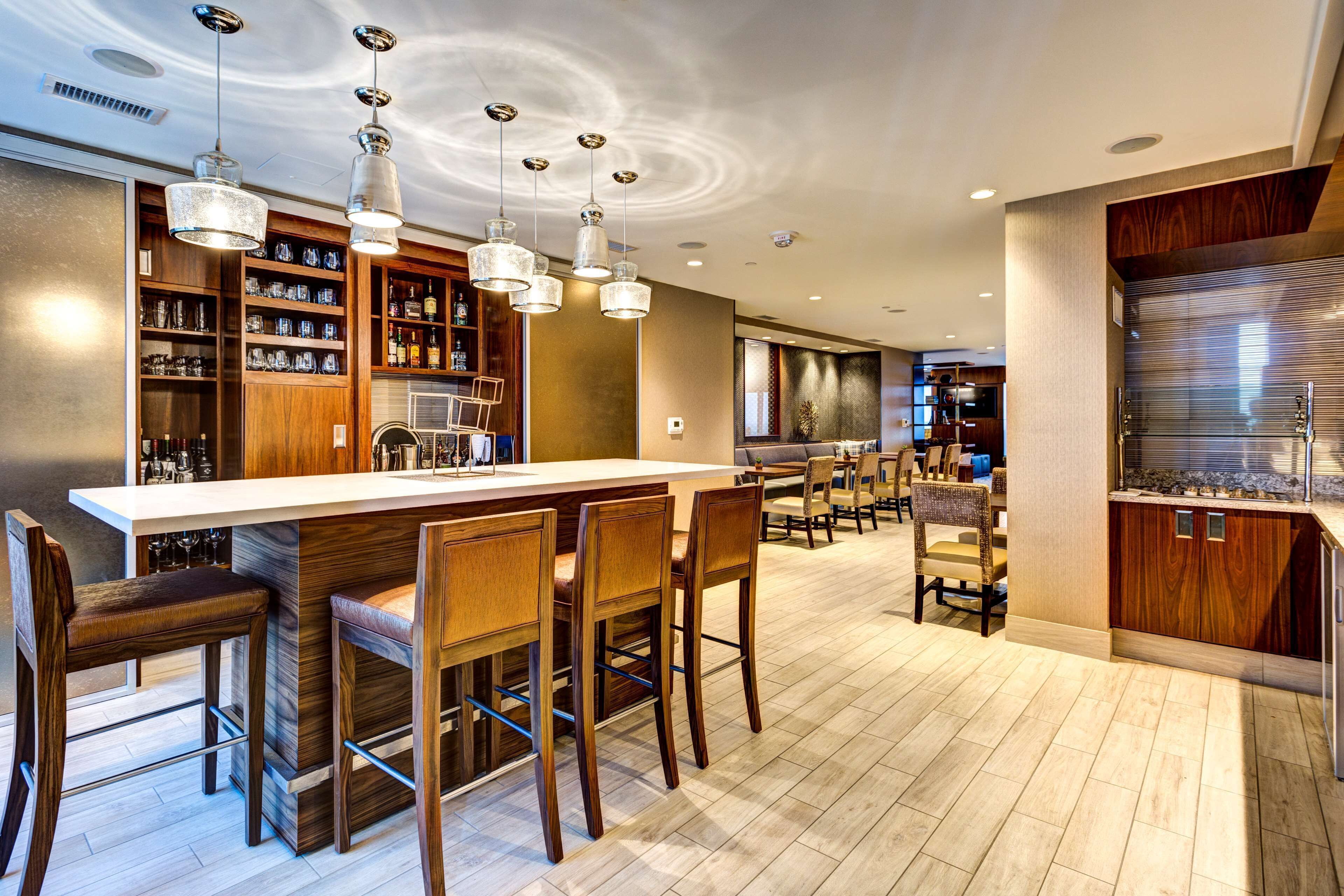 A modern kitchen with a bar area, wooden cabinetry, and pendant lighting.