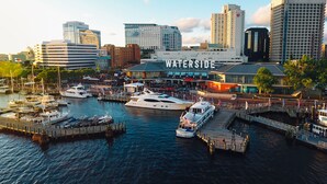 A marina with several boats docked, a waterfront restaurant named 'WaterSide', and modern buildings in the background. - Hilton Norfolk The Main (Norfolk)