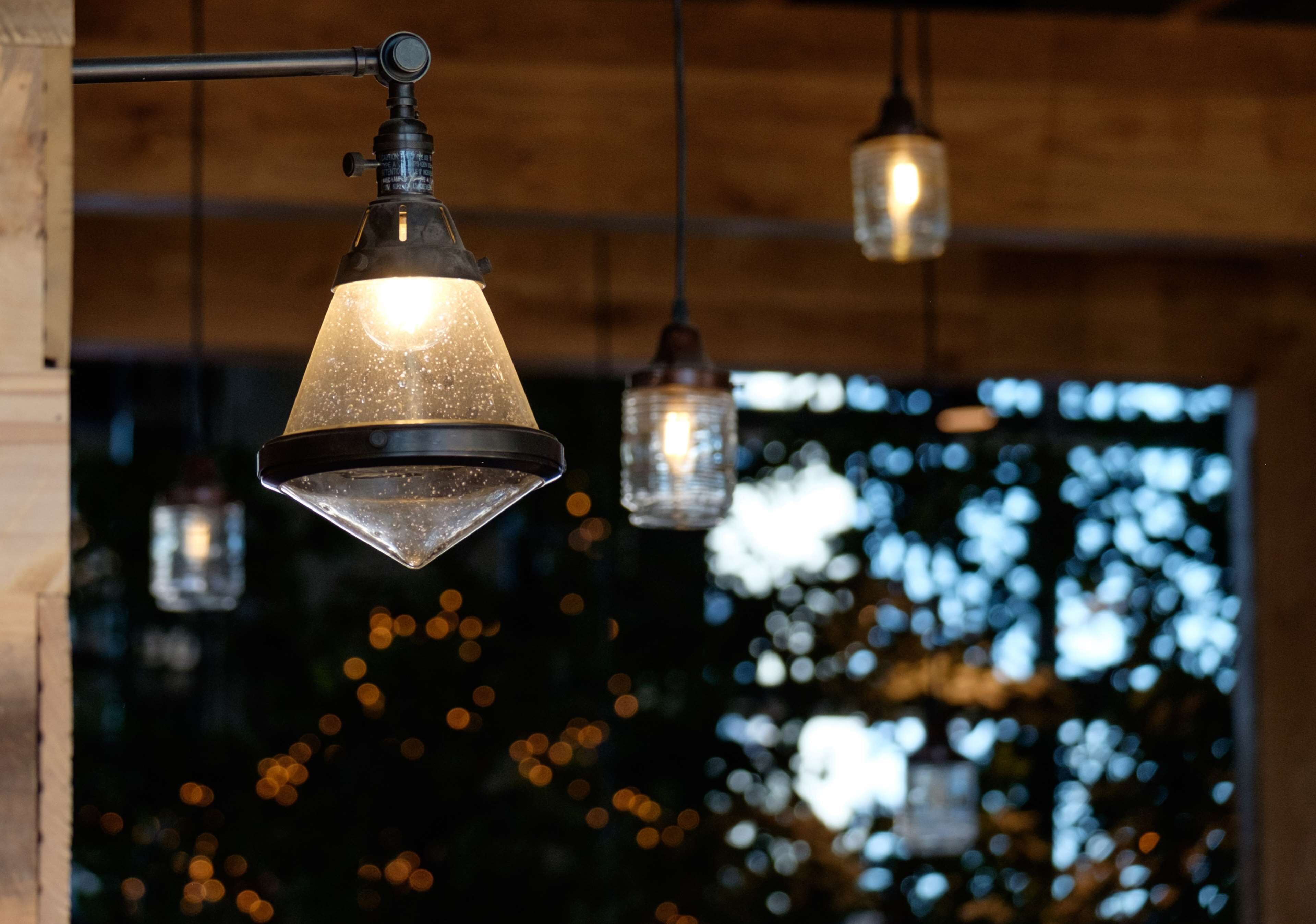 A hanging light fixture with a clear glass shade, suspended from a wooden ceiling.
