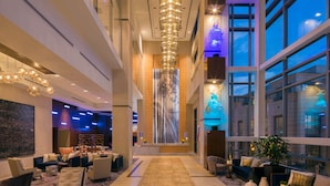 A spacious lobby with a central walkway, seating areas, and large windows offering views of the cityscape. - Hilton Norfolk The Main (Norfolk)