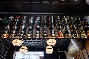 A wine cellar with rows of wine bottles and hanging light fixtures.