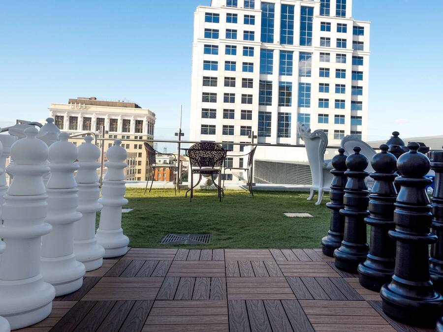 Un tablero de ajedrez dispuesto en una terraza en la azotea, con un paisaje urbano de fondo.