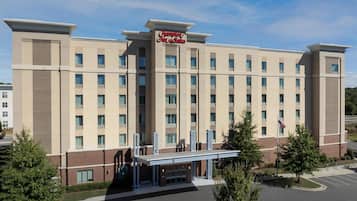 Un grand hôtel à plusieurs étages, reconnaissable à son enseigne bien visible indiquant « Hampton Inn & Suites ».